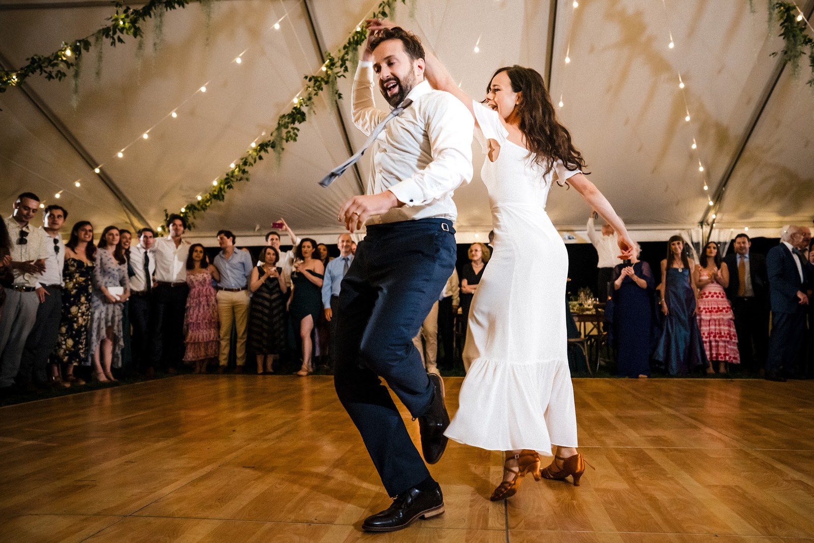 Couple dancing energetically on a dance floor at an outdoor tented Denver reception