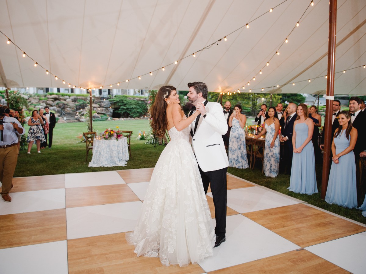 Couple holding hands on a checkerboard dance floor at an elegant Denver wedding reception