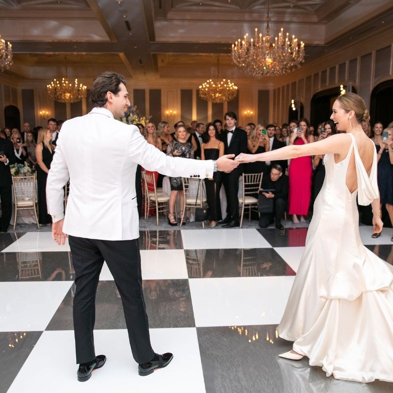 Couple's first dance on a checkerboard patterned dance floor under a tent at a Denver reception